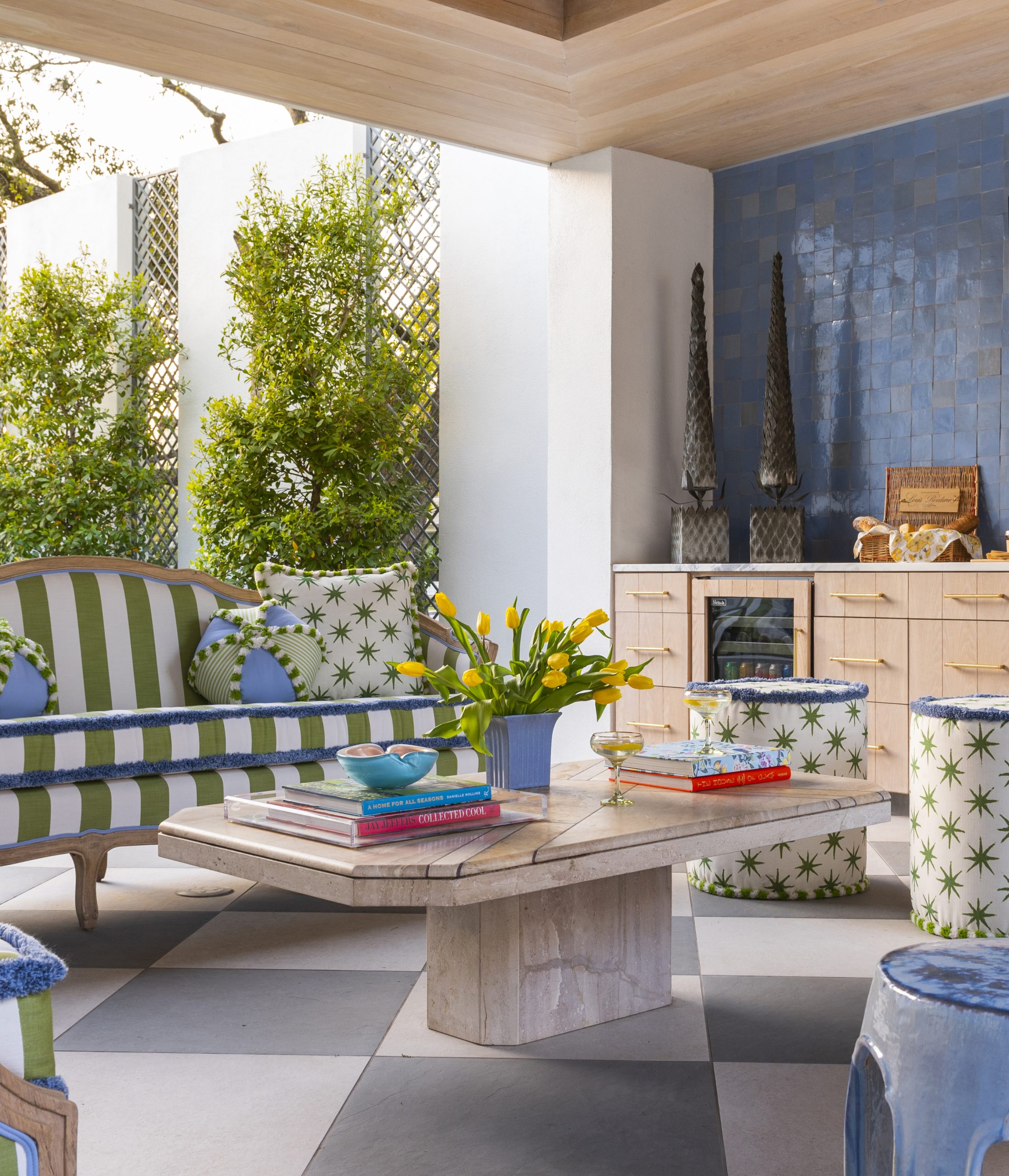 Outdoor covered patio with green and white striped couch, built ins, and coffee table