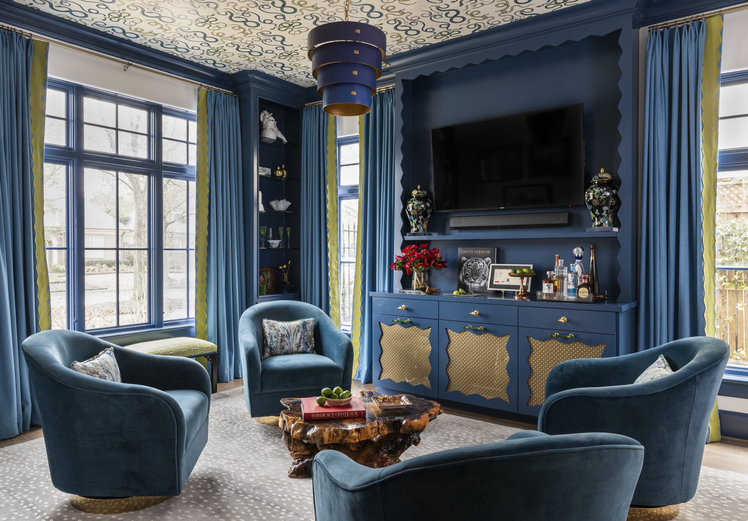 Lounge Room with snake print wallpaper on ceiling, deep blue trim, cabinetry, drapery and chairs, with scalloped details throughout by Creative Tonic