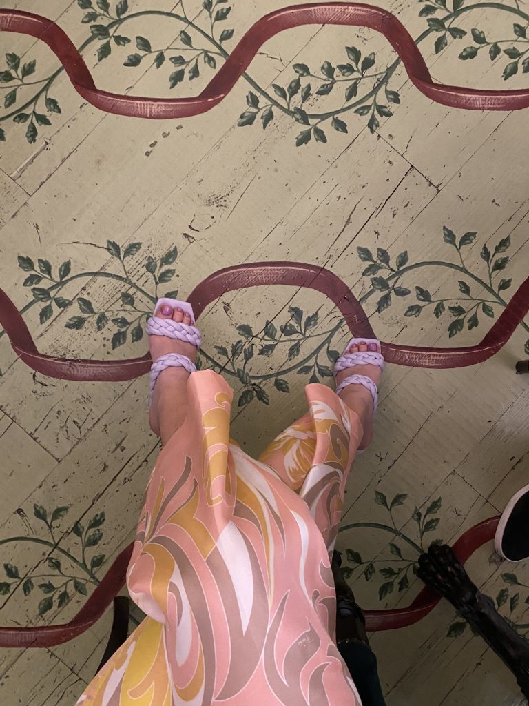 Woman in long dress and lavender sandals showing the artful floors at Gucci Osteria, Florence Italy