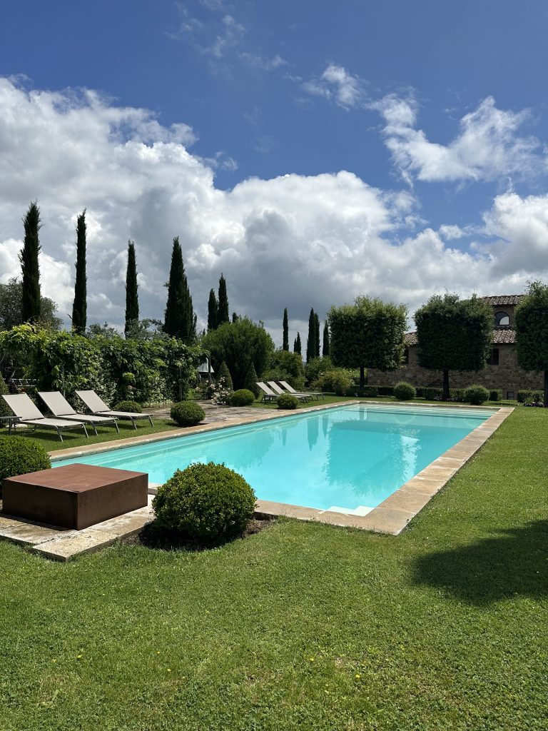 Pool surrounded by green grass at villa in Tuscany